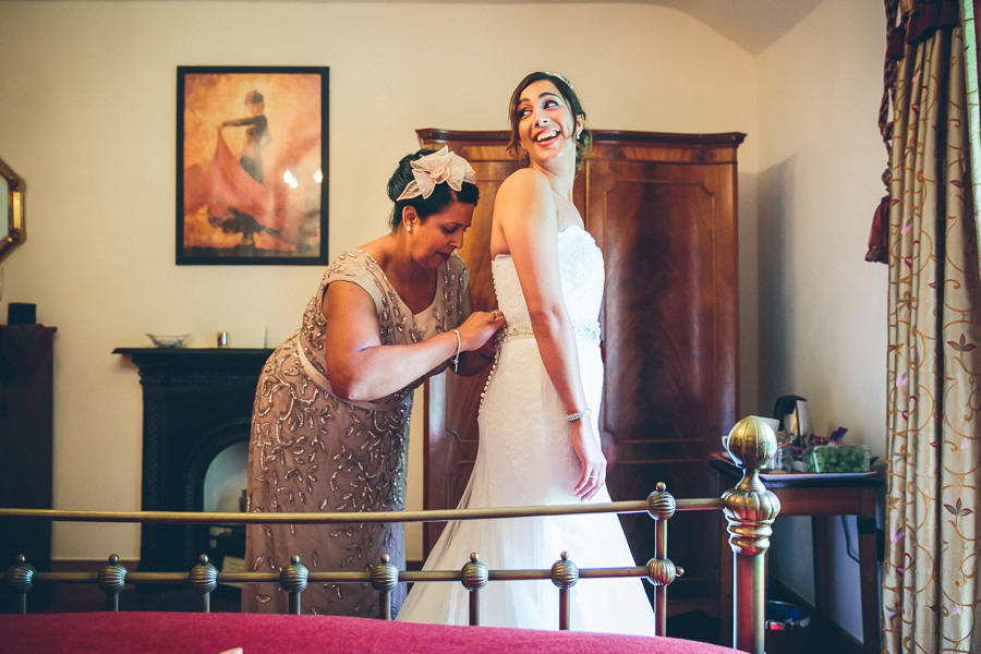mother of bride fastening brides dress